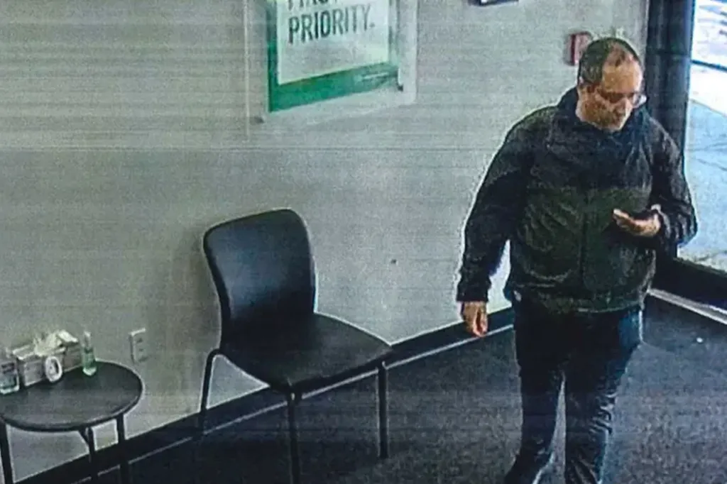 Claudio Manuel Neves-Valente looking at his phone at an Alamo rental car center.