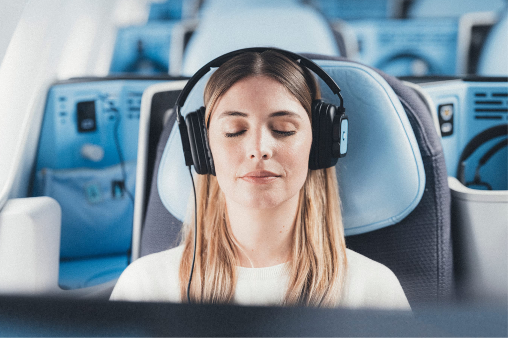 Woman with headphones relaxing in an airplane seat.