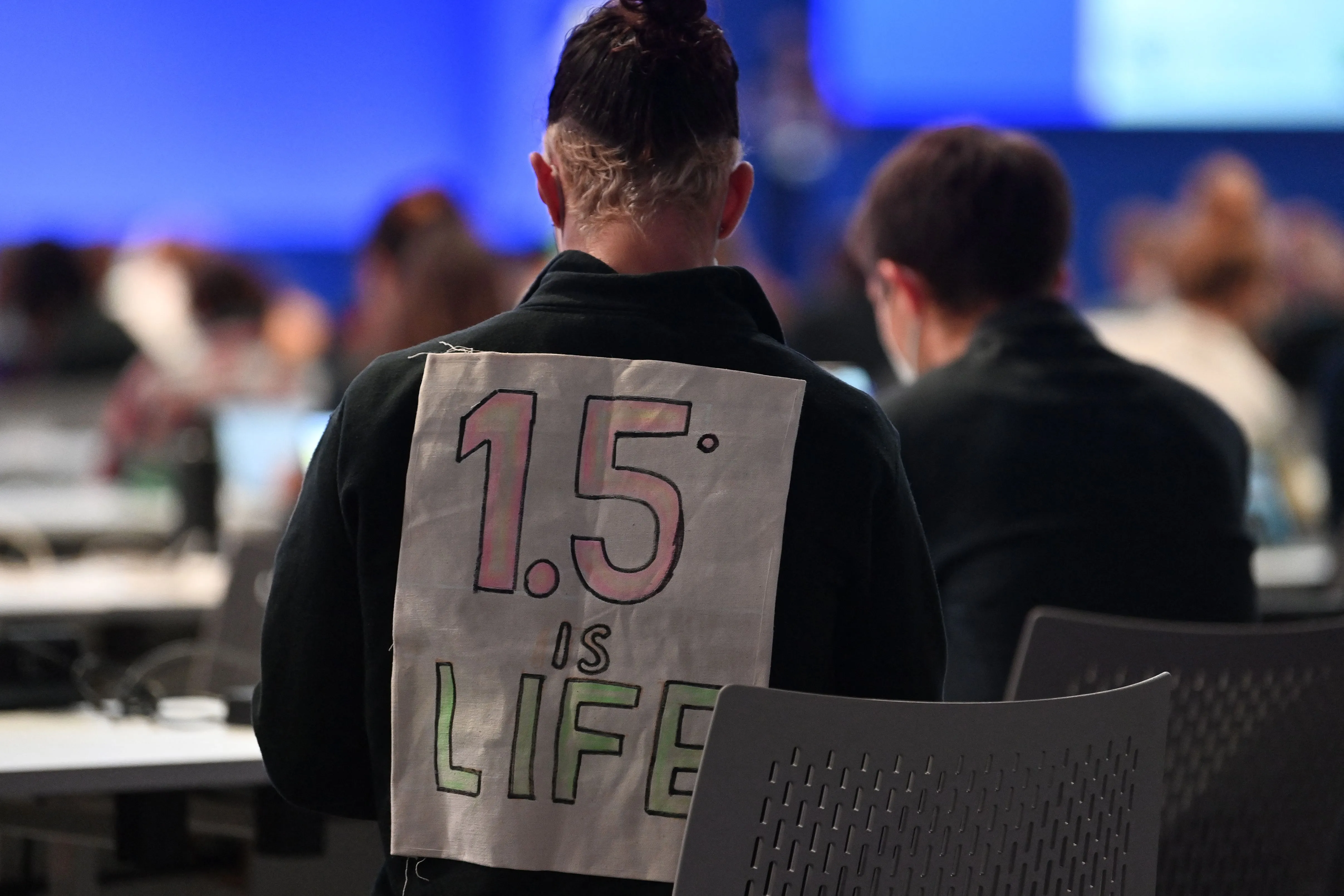 A sign posted behind someone’s back reads “1.5C is life” A sign posted behind someone’s back reads “1.5C is life”