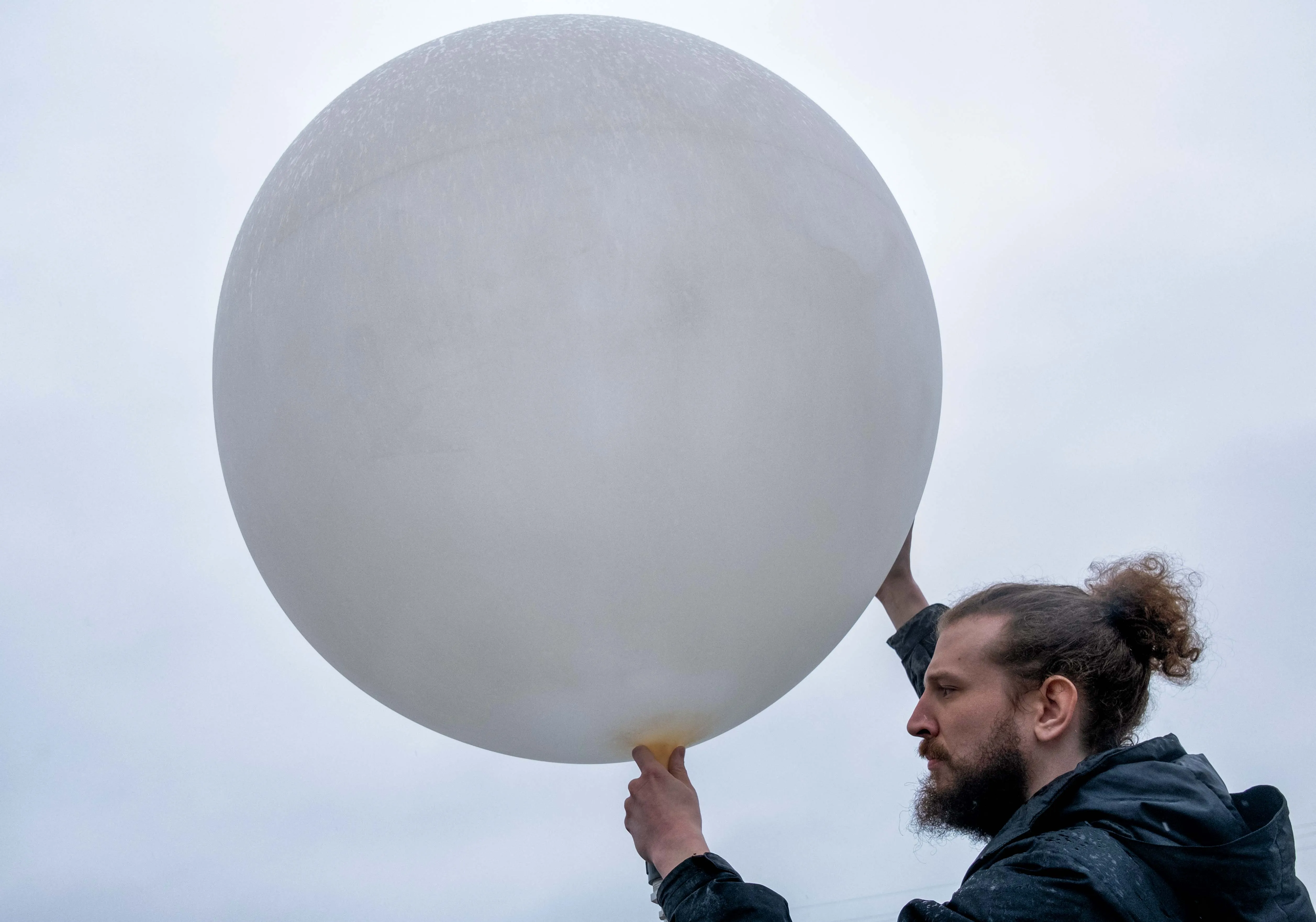 A member of a weather team prepares a weather balloon for release