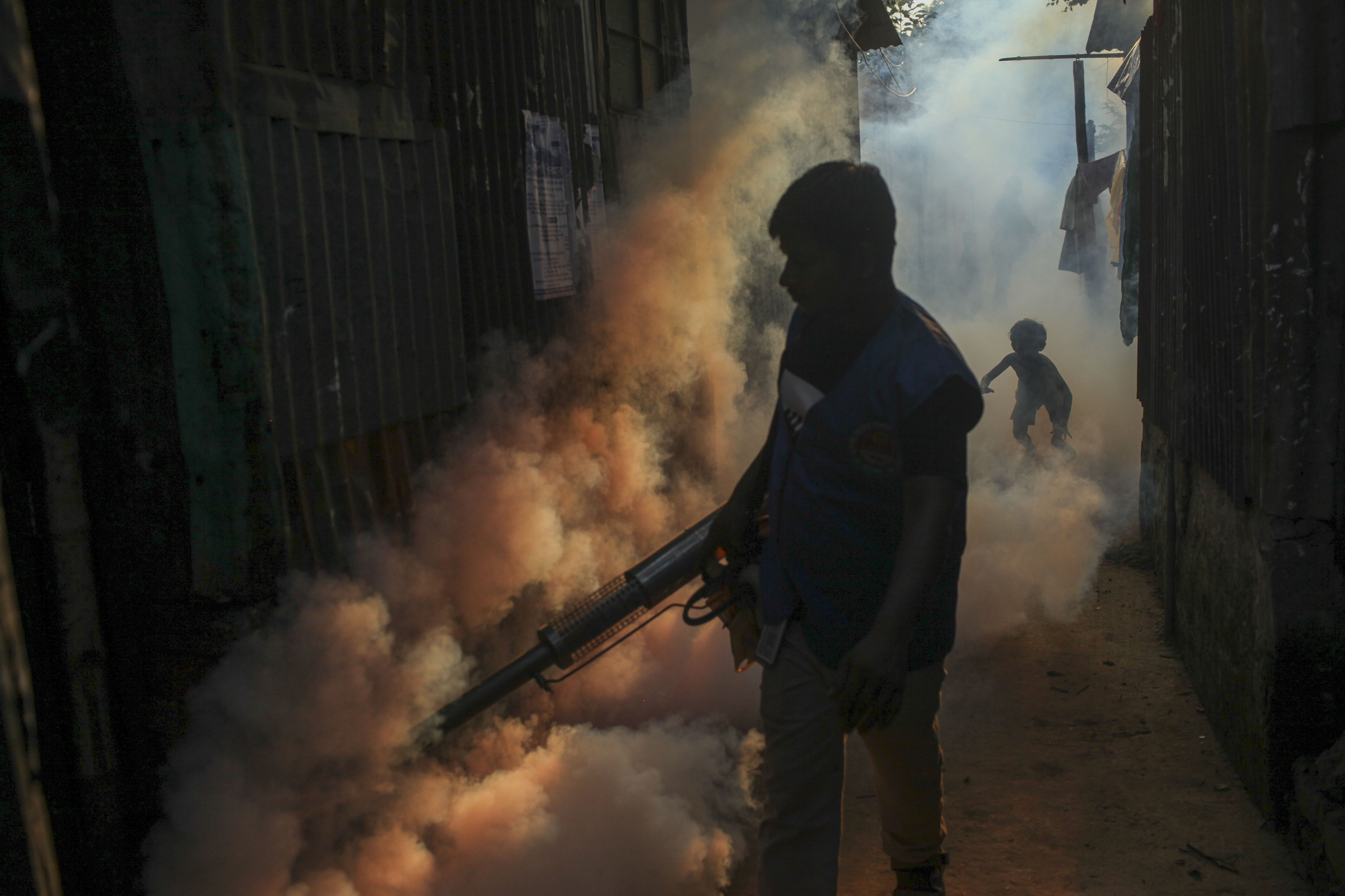 A worker fumigates an alleyway in a densely populated neighborhood to kill mosquitoes A worker fumigates an alleyway in a densely populated neighborhood to kill mosquitoes
