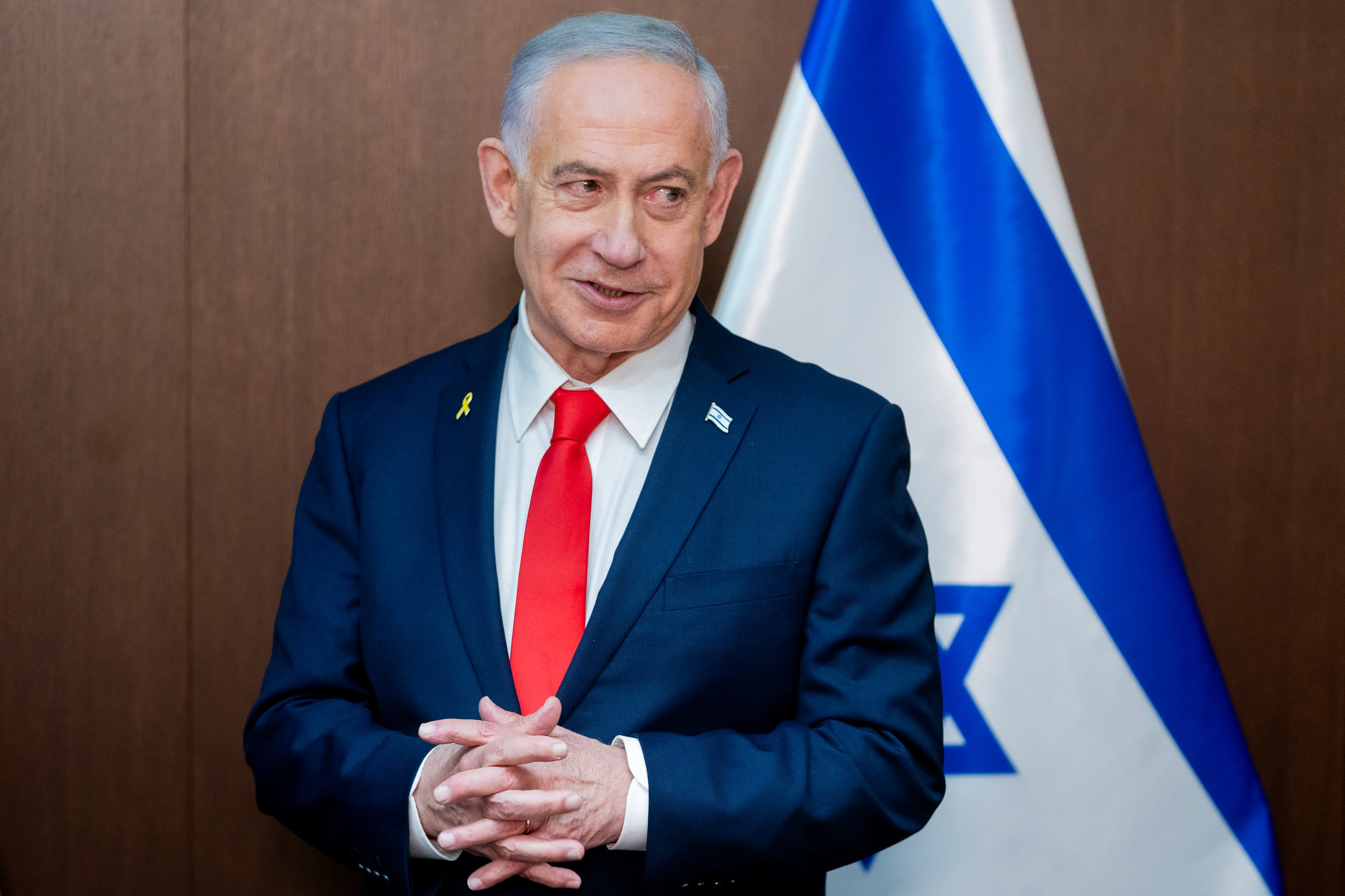 Benjamin Netanyahu standing in front of an Israeli flag.