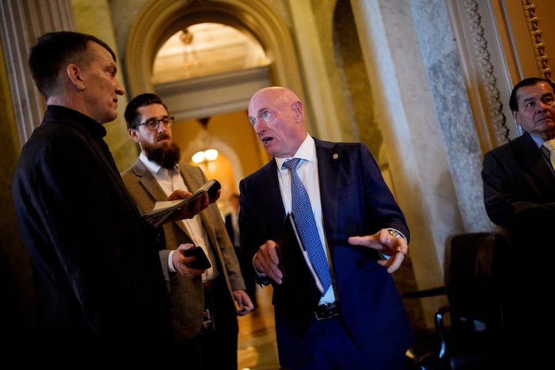 WASHINGTON, DC - DECEMBER 11: Sen. Mark Kelly (D-AZ) speaks to reporters as he walks into the Senate Chamber on December 11, 2025 in Washington, DC. Two opposing health care bills intended to avert rising health care premiums failed.
