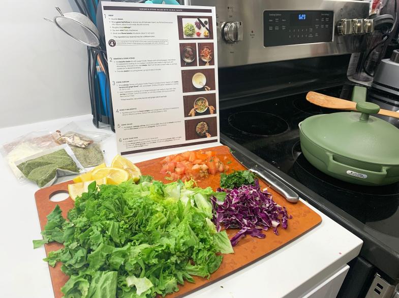 A cutting board with veggies and a recipe card