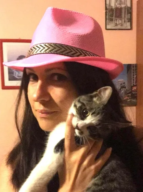 A woman in a pink hat holding a cat.