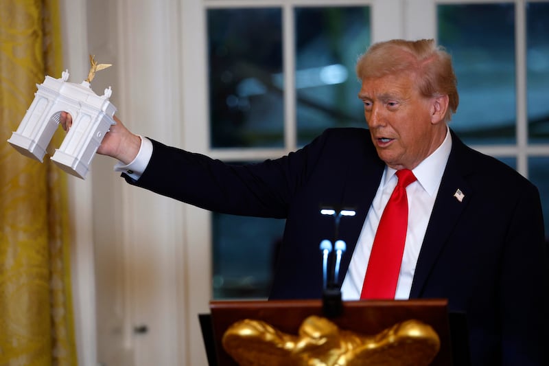 President Donald Trump holds a model of an arch as he delivers remarks during a ballroom fundraising dinner in the East Room of the White House on October 15, 2025 in Washington, DC.