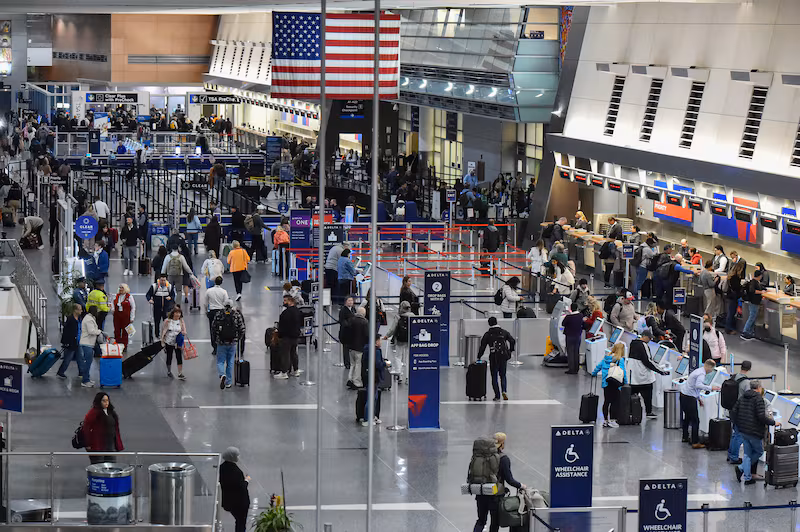 Travelers check in for flights at Boston Logan International Airport in Boston, Massachusetts on November 10, 2025. The US Senate took a major step on November 9 toward ending the longest government shutdown in American history when it cleared the way for a formal debate on a motion to resume funding to federal agencies. The deal between Democratic and Republican senators, just the first step to halting the shutdown, came as authorities warned US air travel could soon "slow to a trickle" as thousands more flights were cancelled or delayed over the weekend. (Photo by Joseph Prezioso / AFP) (Photo by JOSEPH PREZIOSO/AFP via Getty Images)