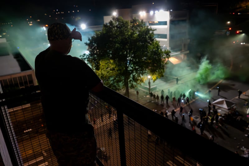 Doyle, a resident of the Grey's Landing apartment building directly across the street from the Immigration and Customs Enforcement facility (ICE), shields his eyes from the flood lights