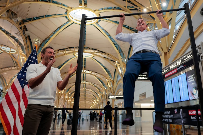Influencer Dr. Paul Saladino watches Transportation Secretary Sean Duffy do pull-ups after his press conference at Reagan Washington National Airport.