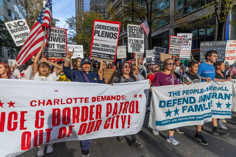 Protesters march through uptown after gathering at First Ward Park for the "No Border Patrol In Charlotte" rally