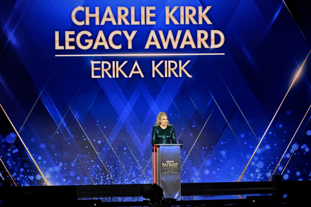 Erika Kirk at a podium on a stage with a screen displaying