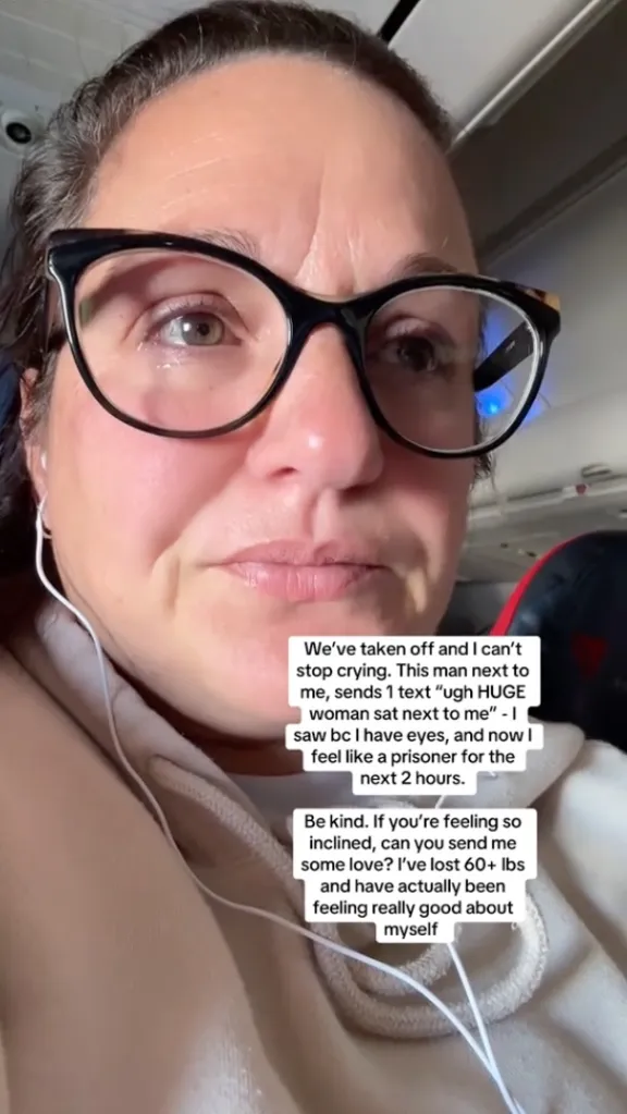 A woman with glasses and earphones cries while on an airplane after a man next to her sent a text calling her a 
