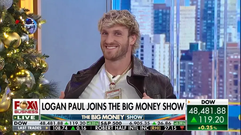 Logan Paul smiles while wearing a large chain with a pendant on Fox Business, with stock market information on the bottom of the screen.