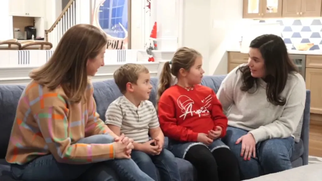Two women and two children sit on a blue sofa.