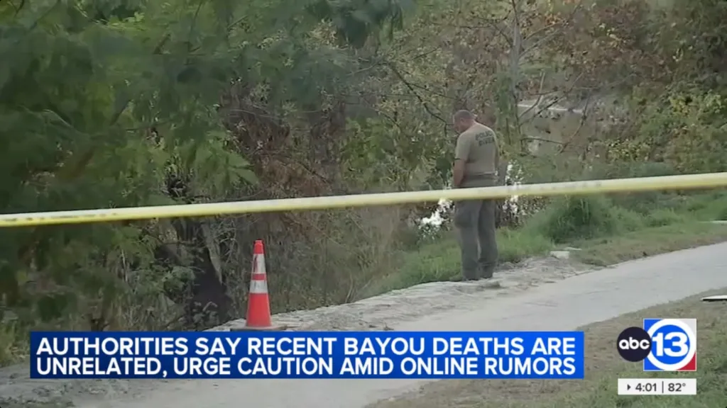 A police diver standing behind crime scene tape next to a body of water.