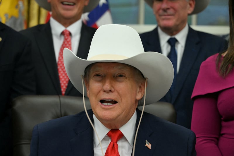 TOPSHOT - US President Donald Trump wears a cowboy hat during a bill signing ceremony with members of the 1980 US Olympic men's ice hockey team in the Oval Office of the White House in Washington, DC, on December 12, 2025. The legislation will award all of the players with Congressional Gold Medals to recognize the 45th anniversary of the US victory at the 1980 Winter Olympic Games. (Photo by Jim WATSON / AFP via Getty Images)