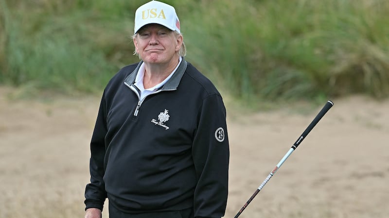 US President Donald Trump reacts after playing from the first tee to officially open the Trump International Golf Links course