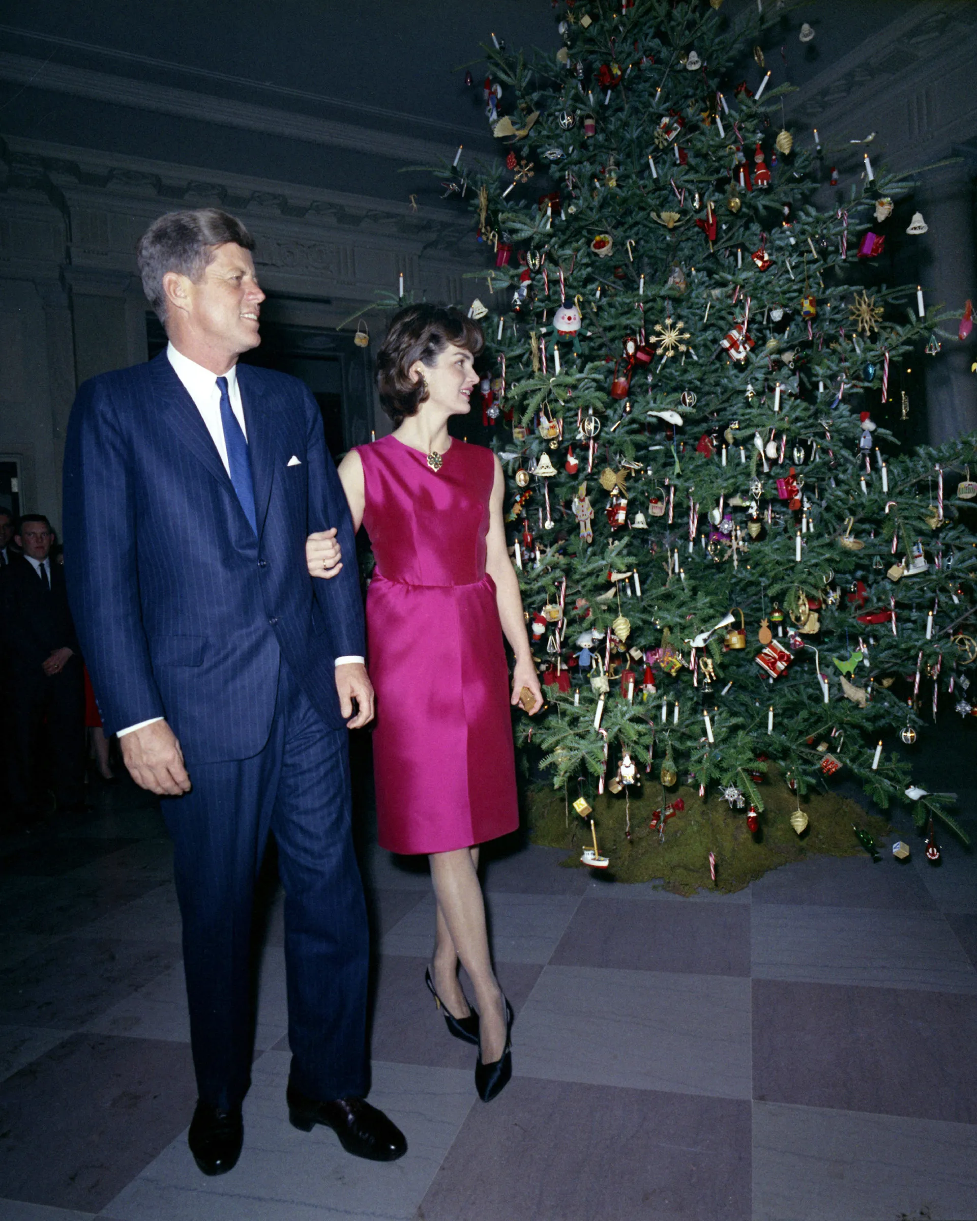 President and Mrs. Kennedy Make an Appearance at the White House Staff Christmas Party near the Christmas Tree in the Cross Hall, 12/12/1962