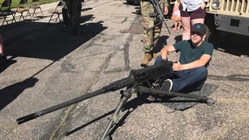 Robinson is seen posing with an M2 Browning 50 calibre machine gun.
