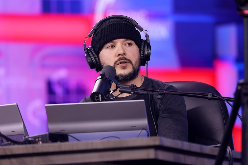 Tim Pool speaks into a microphone on stage at the 2024 AmericaFest at the Phoenix Convention Center in Arizona/