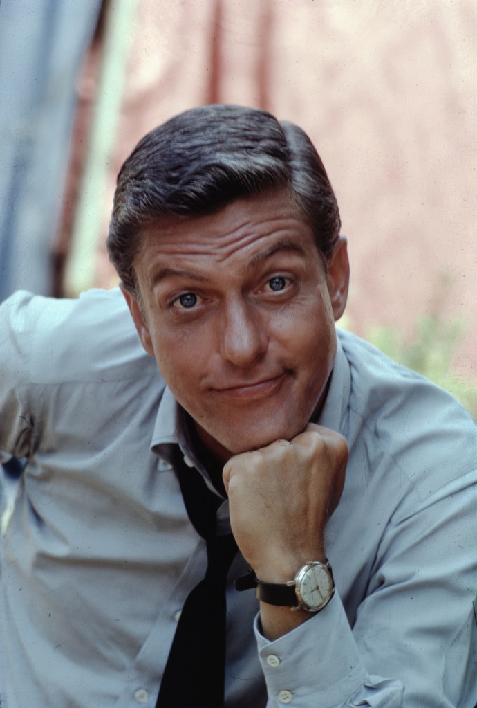 Dick Van Dyke in a blue shirt with his hand on his chin.