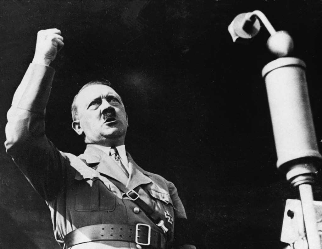 Adolf Hitler giving an impassioned speech, raising his fist at the Berlin International Auto Show.