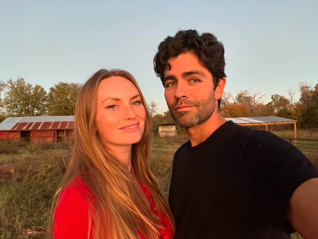 Adrien Grenier and Jordan Roemmele pose outdoors in a sunset. 