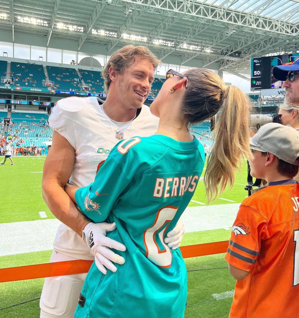 Alix Earle and Braxton Berrios share a hug on a football field.