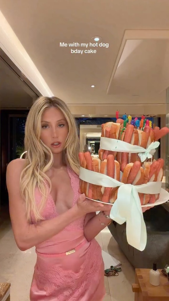 Alix Earle posing with a hot dog cake.