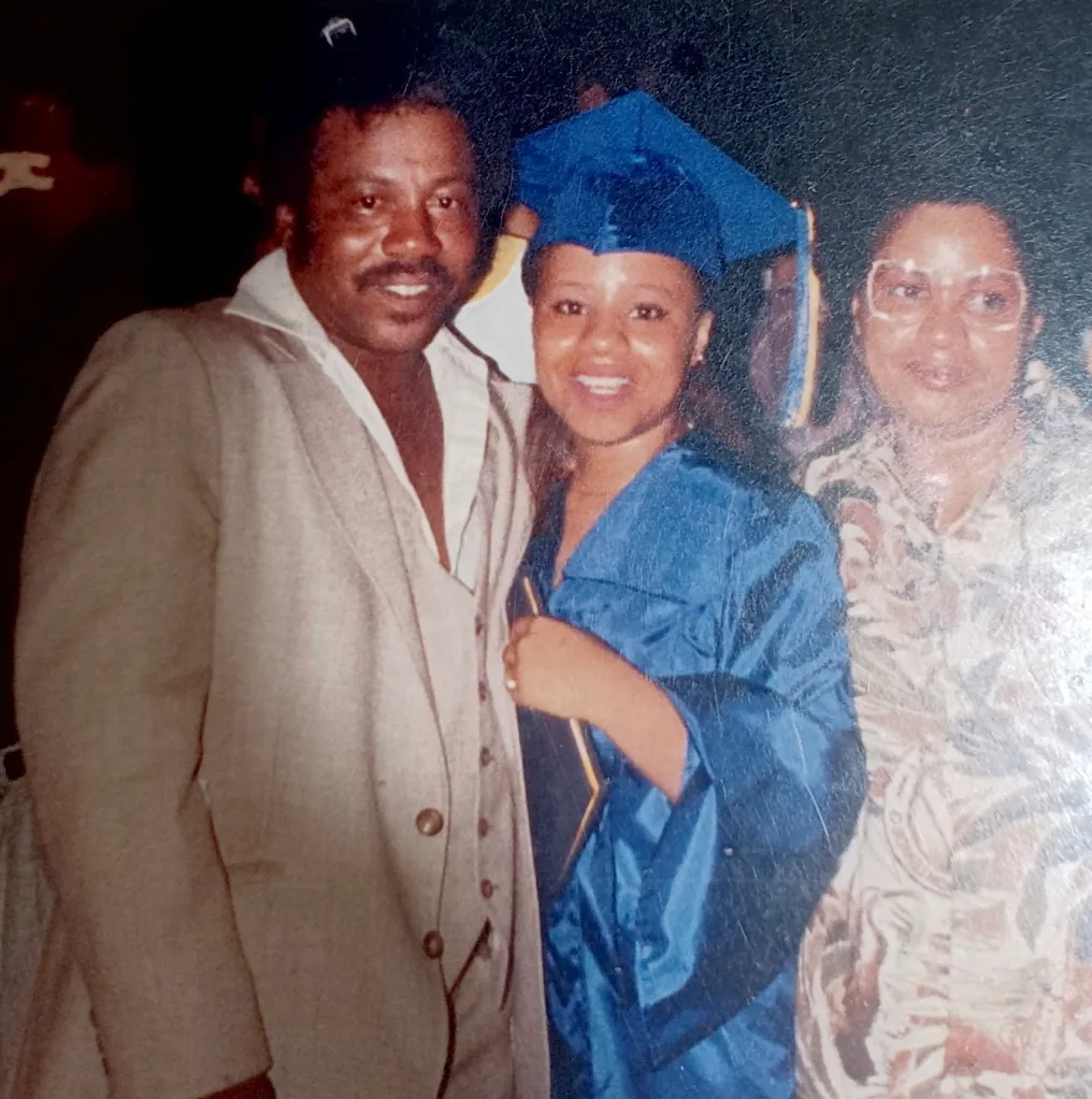 Lovetta Little-Smith in a blue graduation cap and gown with her father Almond Gene Little and Lovie Sneed.