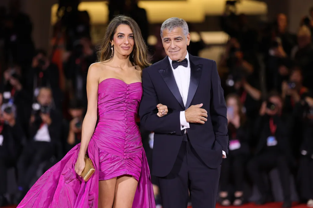 Amal Clooney in a fuchsia gown with George Clooney in a tuxedo at the 82nd Venice International Film Festival.