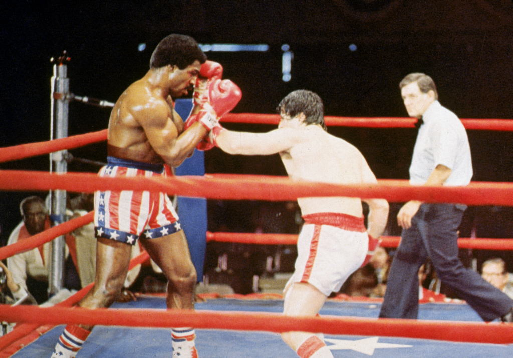 Stallone, as Rocky Balboa, punches American actor Carl Weathers, as Apollo Creed, during a boxing match in a still from the film, 'Rocky,' directed by John G Avildson.