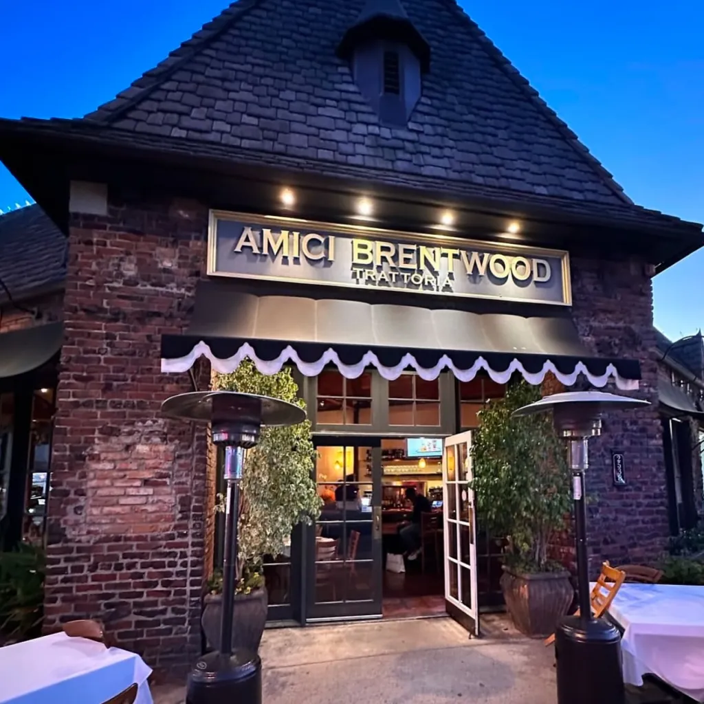 Exterior view of Amici Brentwood Trattoria with a brick facade and dark awning.