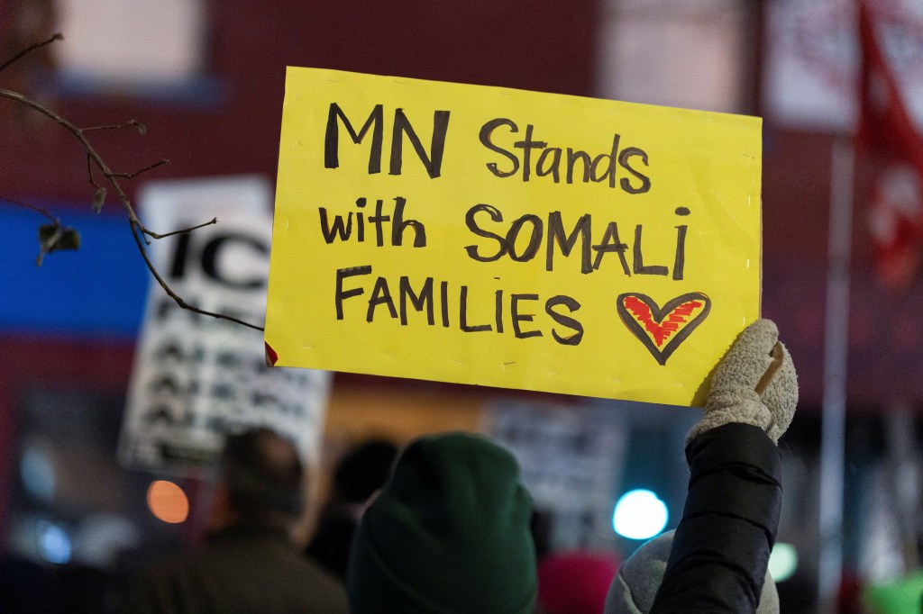 A protester holds a yellow sign reading