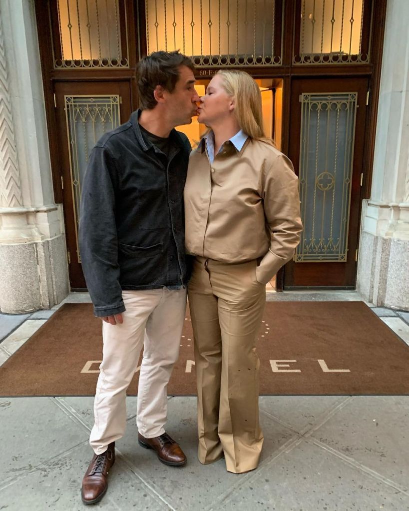 Amy Schumer and her husband Chris Fischer kissing in front of a building.