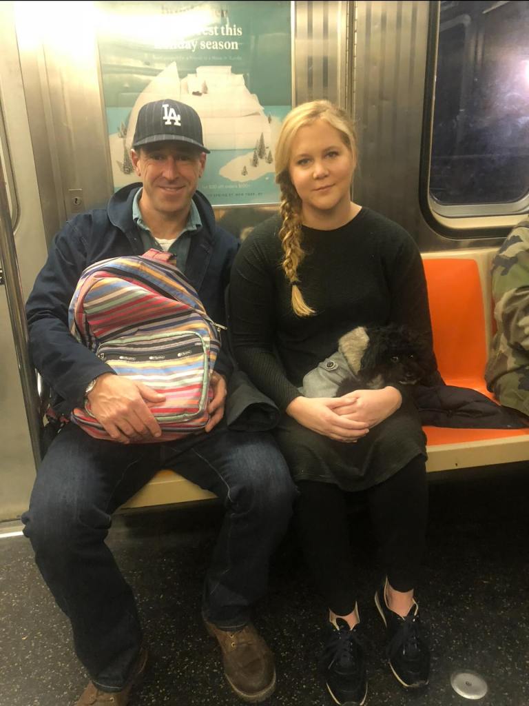 Amy Schumer and Chris Fischer on a subway train with their dog.