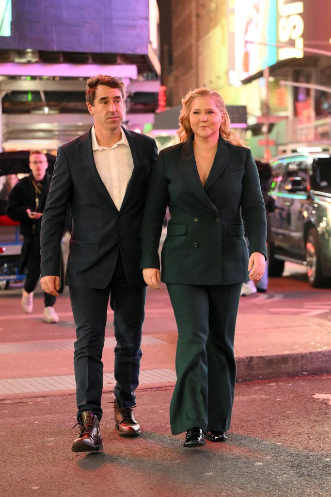 Amy Schumer and Chris Fischer walking, in suits, at night.