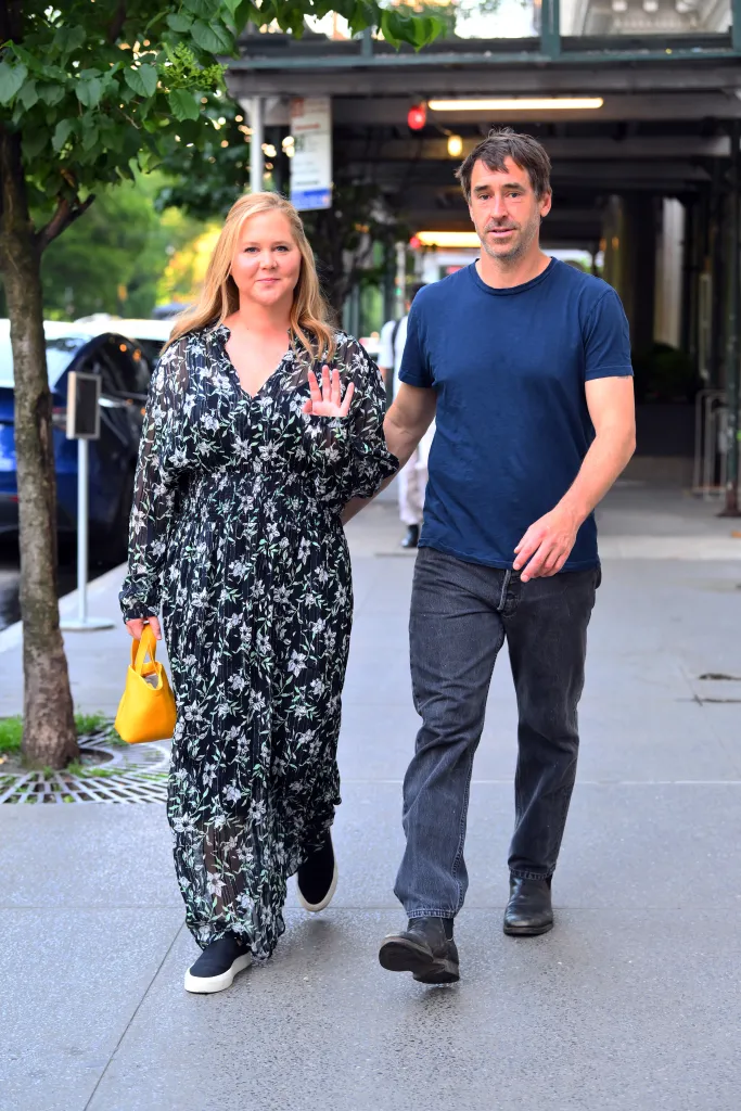 Amy Schumer and Chris Fischer walking together on a city sidewalk.