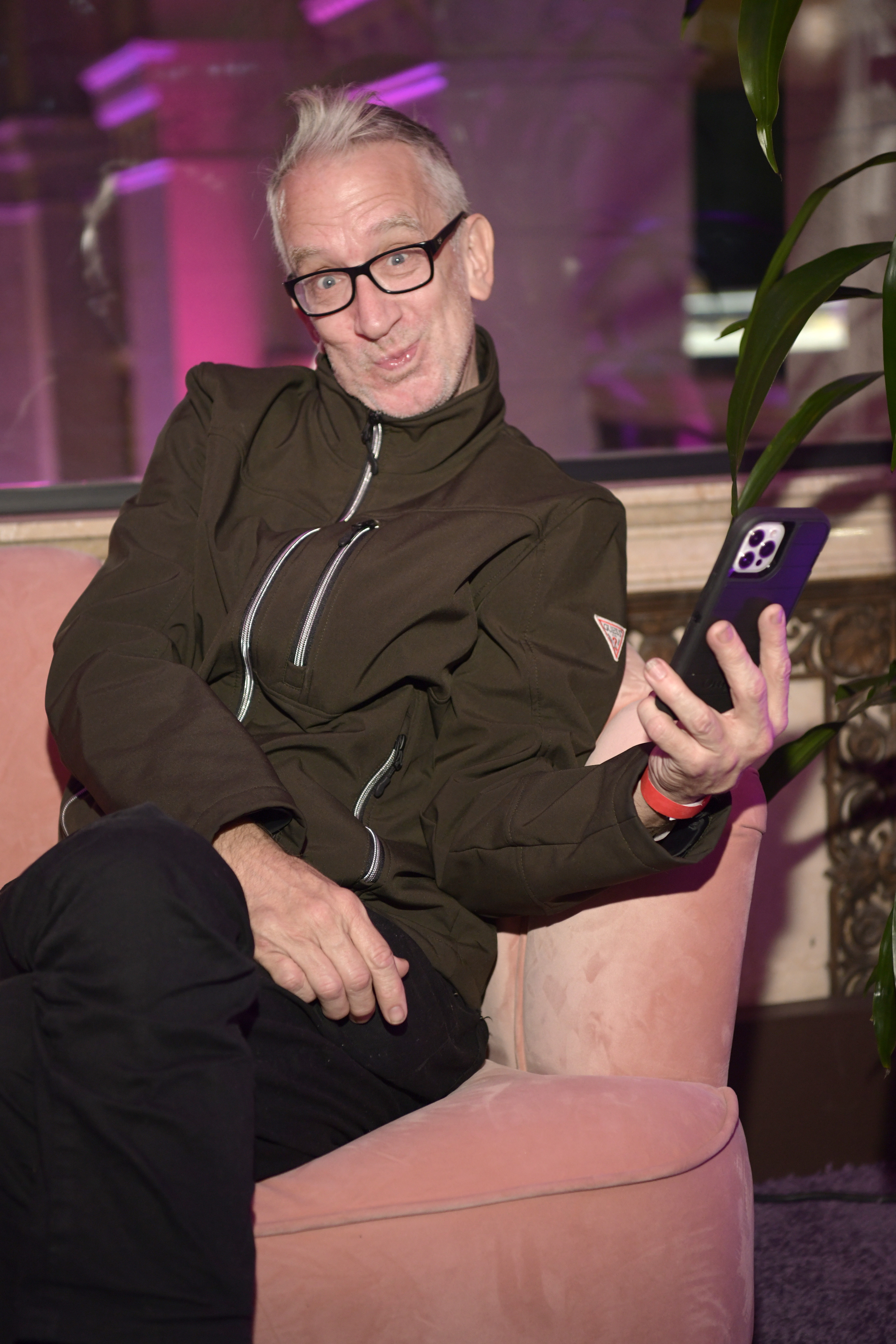 Andy Dick front row at Los Angeles Fashion Week, holding a phone.