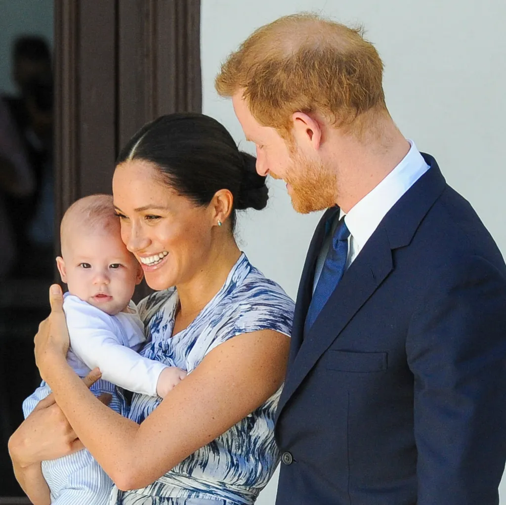 Meghan Markle holding her son Archie, with Prince Harry looking at them.