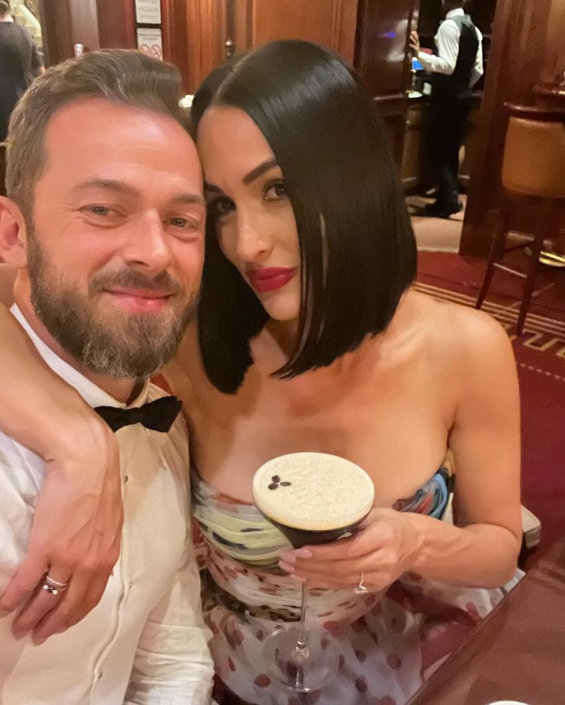 Artem Chigvintsev and Nikki Bella smiling, with Nikki holding a drink.