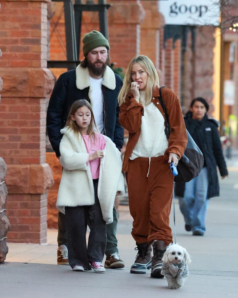 Kate Hudson in a rust corduroy outfit, her fiancé Danny Fujikawa, and their daughter Rani Rose, with a dog on a leash, on a street in Aspen.