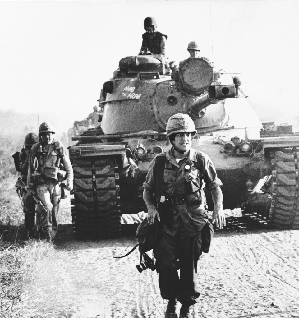 Arnett walks in front of a U.S. tank in Vietnam, 1967.