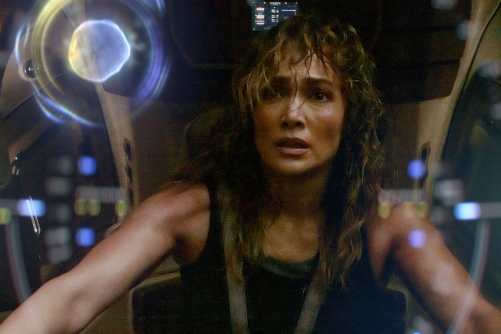 Jennifer Lopez as Atlas in a sci-fi cockpit, with glowing data visible on a screen.