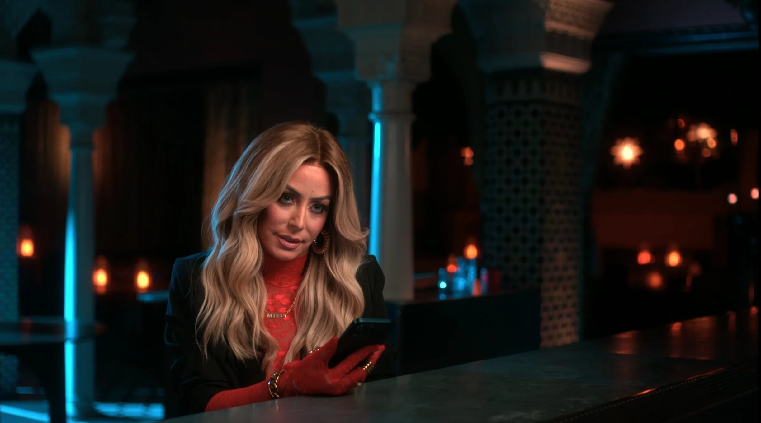Aubrey O'Day looking at her phone at a bar.