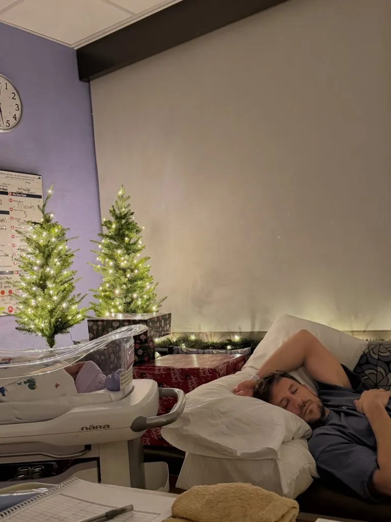 JoJo Fletcher and Jordan Rodgers with their newborn baby, two Christmas trees, and a man sleeping.
