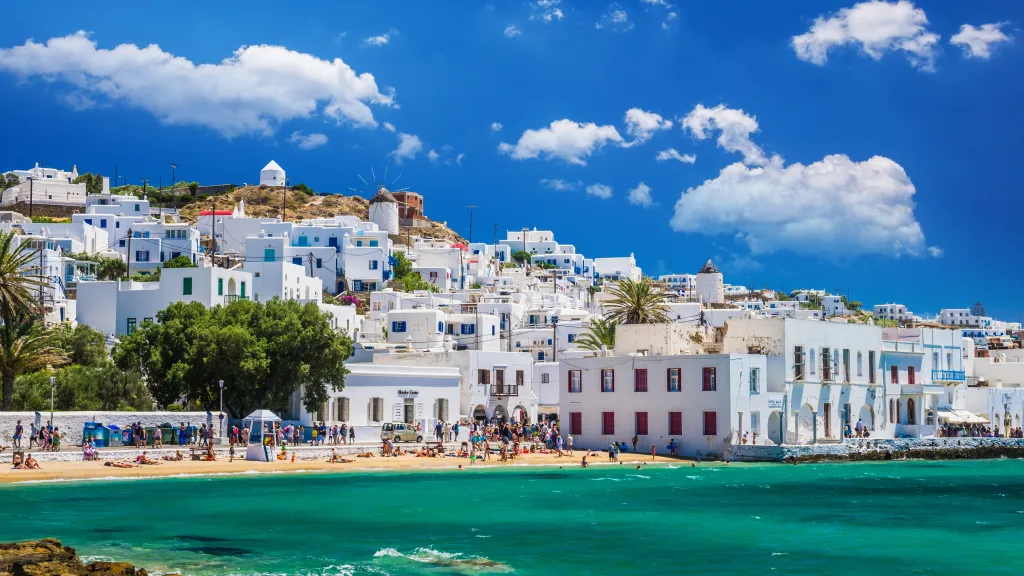 View of Mykonos town with white houses, an old harbor, and boats.