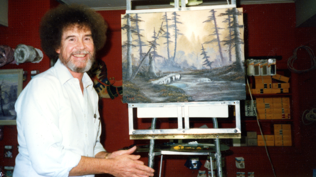 Bob Ross shows off one of his paintings