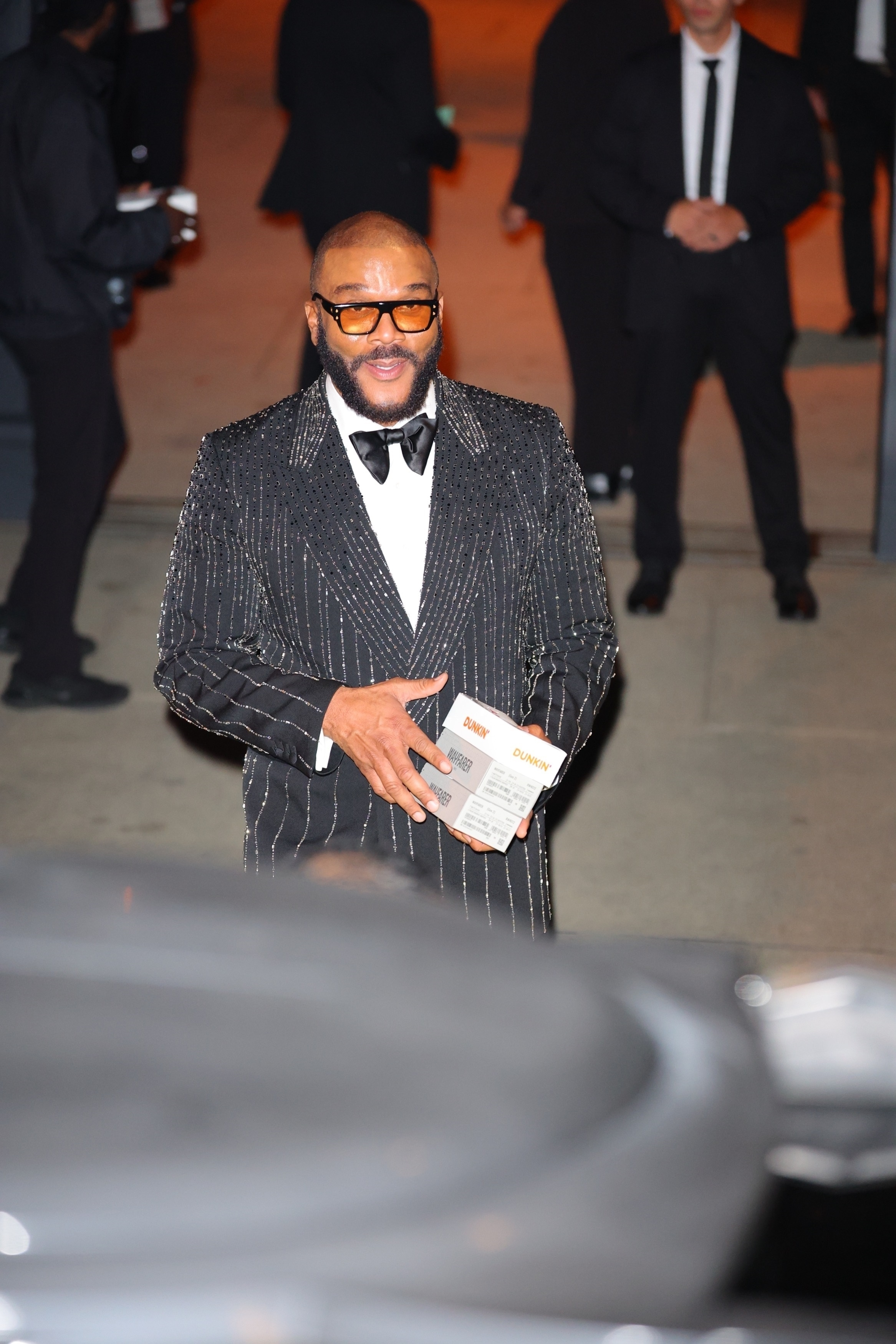 Tyler Perry holding two Dunkin' Wayfarer boxes.