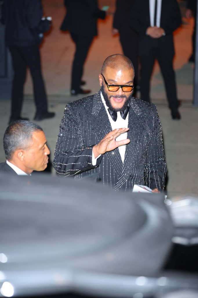 Tyler Perry in a black sequined suit and orange-tinted sunglasses.